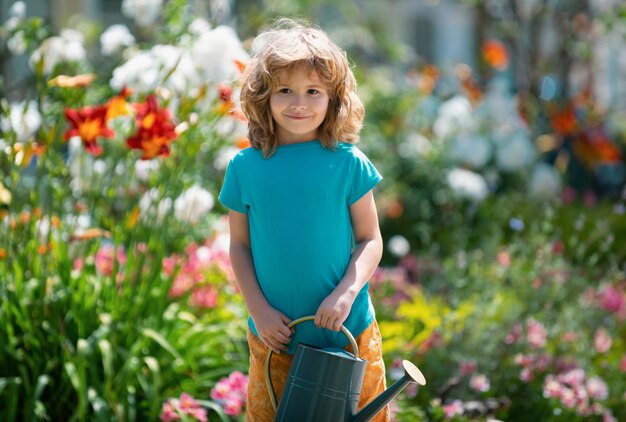 庭の家の園芸で花に水をまくアメリカの子供時代の子供