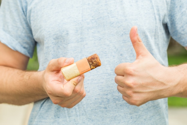american man eating energetic cereals bar very happy pointing with hand and finger to the side
