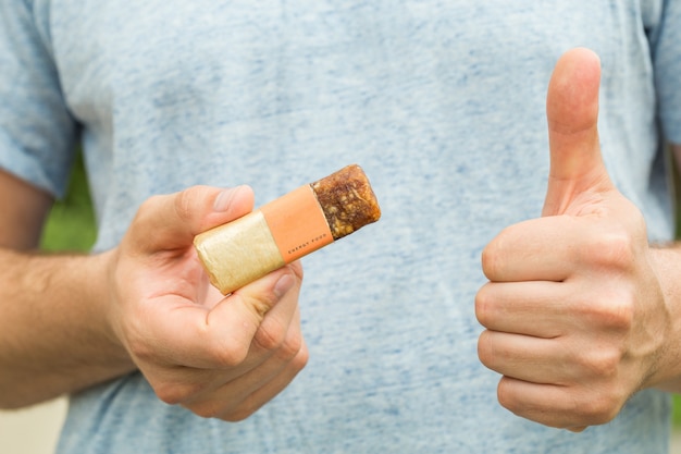 american man eating energetic cereals bar very happy pointing with hand and finger to the side