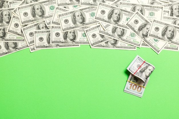 텍스트 비즈니스 머니 개념을 위한 빈 공간이 있는 색색의 배경 상단 보기에 있는 미국 돈. 현금 스택과 함께 100 달러 지폐입니다.