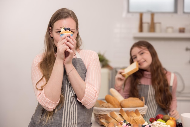 アメリカ人の母と娘がカップケーキを握って互いに微笑んでいます