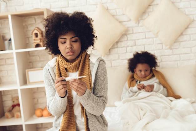 Madre americana e figlia che si siedono sul letto a casa.