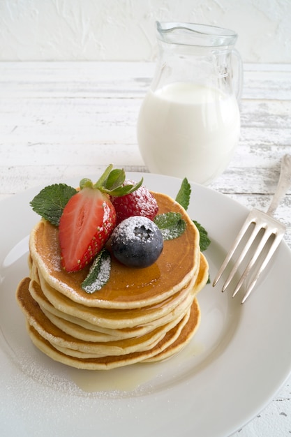 American pancakes with berries on a light background.