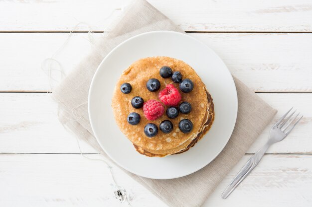 American pancakes with raspberries and blueberries on white wooden table