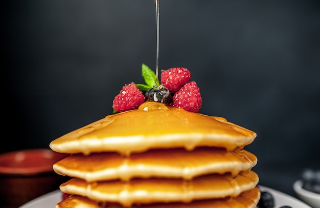 American pancakes with raspberries, fresh blueberries and honey. Healthy breakfast on concrete
