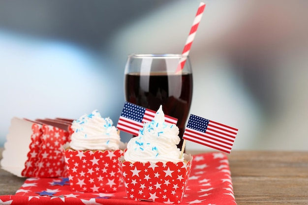 American patriotic holiday cupcakes and glass of cola on wooden table