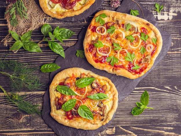 American pizza with mozzarella, tomato, pepperoni on dark wooden table.