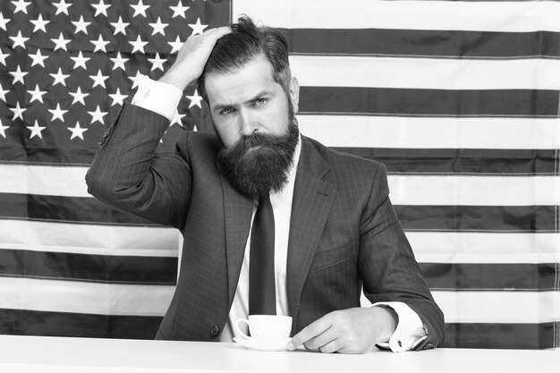 American politician in election his election campaign bearded man drink coffee cup American education reform in july 4 American citizen at USA flag drinking coffee on tribune