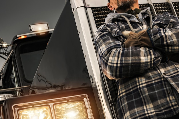 American semi truck driver in front of his tractor truck