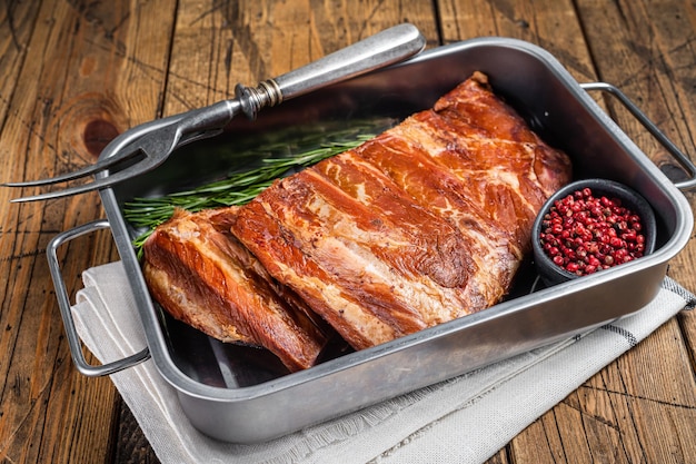 American Smoked Pork spare Ribs in steel tray with herbs Wooden background Top view