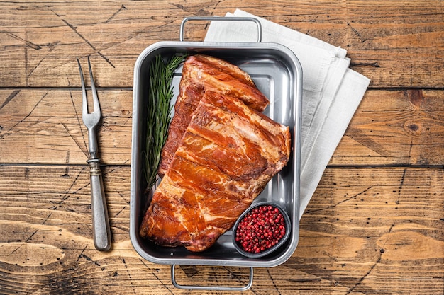 American Smoked Pork spare Ribs in steel tray with herbs Wooden background Top view