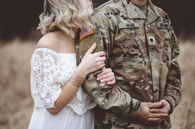 Американский солдат с любящей женой стоят на сухом травянистом поле