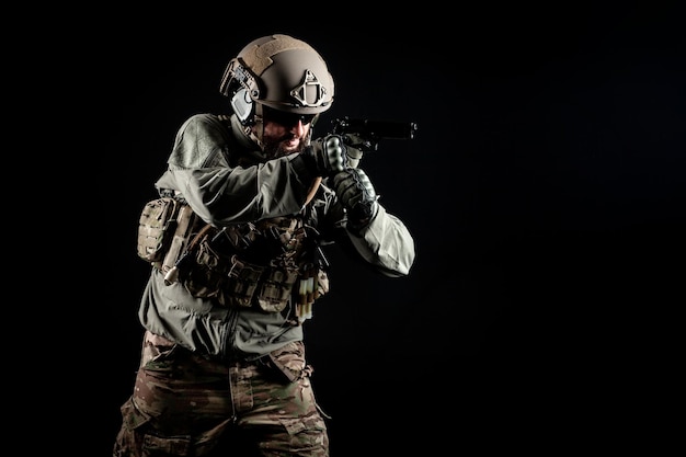 Photo american special forces a soldier in a military uniform with a weapon attacks on a black background