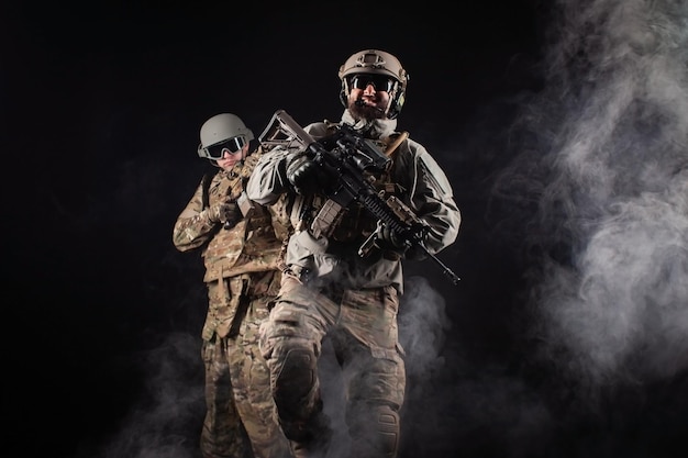 American special forces two soldiers in military uniform with weapons on a dark background