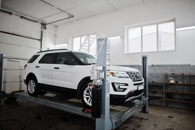 American SUV car on stand for wheels alignment camber check in workshop of service station