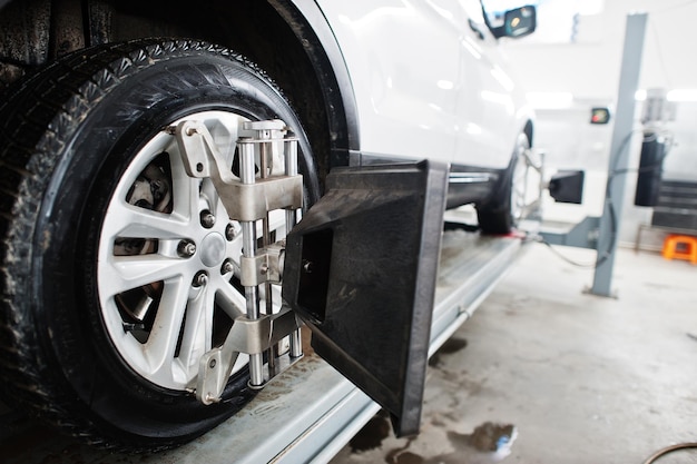 American SUV car on stand for wheels alignment camber check in workshop of service station