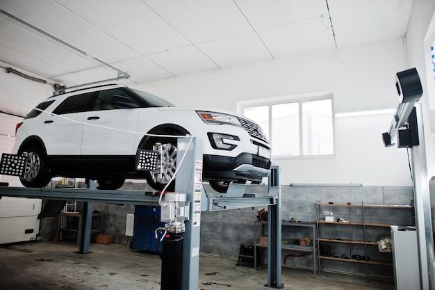 American SUV car on stand for wheels alignment camber check in workshop of service station