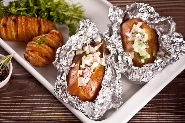 American traditional homemade Hasselback Potato and stuffed potatoes with fresh herbs and bacon. Top view.