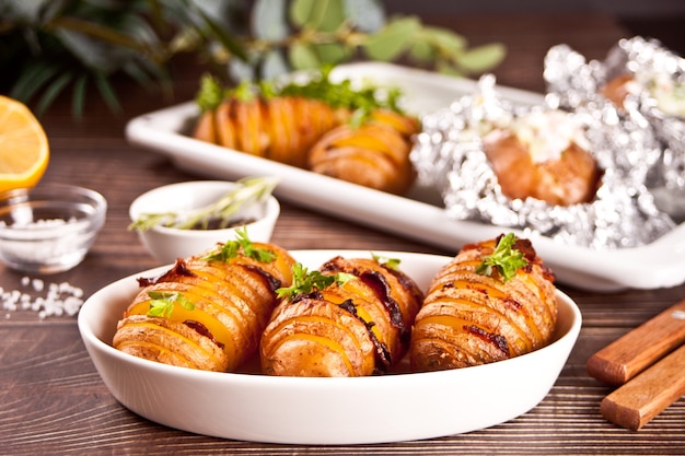 American traditional homemade Hasselback Potato and stuffed potatoes with fresh herbs and bacon.