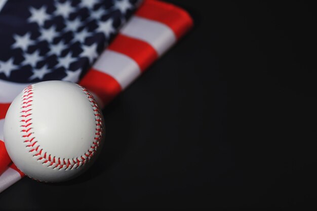 Американская традиционная спортивная игра. Бейсбол. Концепция. Бейсбольный мяч и биты на столе с американским флагом.