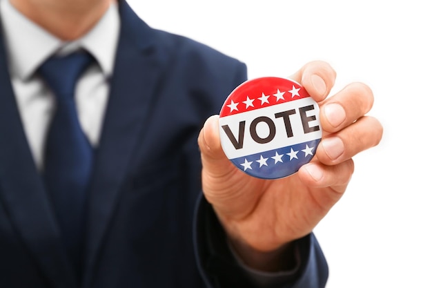 american votes concept man holding voting badge close up