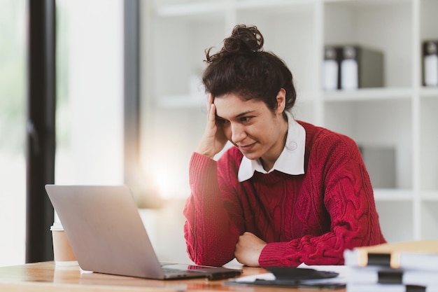 American Woman looking stressed while using laptop with financial document on table Woman work from home