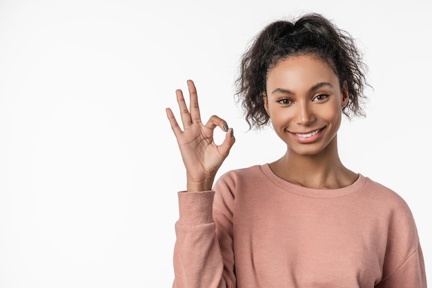 american woman smiling on camera and gesturing ok sign isolated over white background