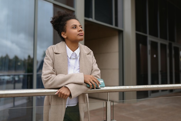 American young woman designer stands thoughtfully in front of a glass business center