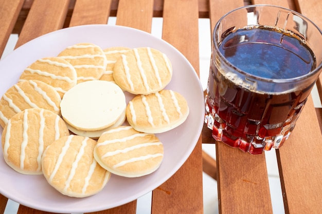 Americano koffie geserveerd in een kristalglas naast witte chocoladekoekjes met citroen en sinaasappel erop