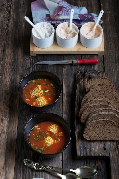 ライ麦パンと素朴なテーブルの上のアメリカンスタイルのトウモロコシとトマトのスープ