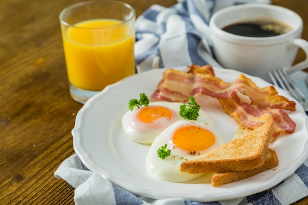 Foto amerikaans ontbijt met zonnige side-up eieren, spek, toast, pannenkoeken, koffie en sap