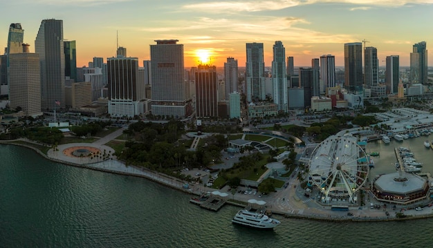 Foto amerikaans stedelijk landschap bij zonsondergang skyviews miami observation wheel bij bayside marketplace met reflecties in biscayne bay water en hoge verlichte wolkenkrabbers van brickell city's financiële centrum