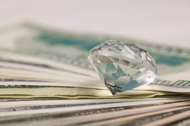 Amerikaanse geldbiljetten met grote diamant close-up Grote hoeveelheid dollars en enorme transparante edelsteen op tafel Zaken en sieraden