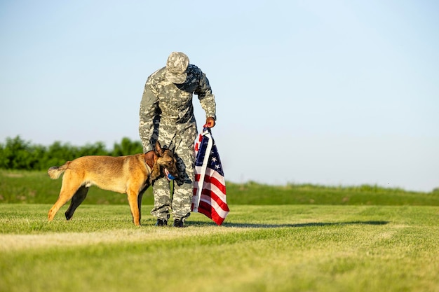 Amerikaanse marinesoldaat die bij zijn militaire hond staat en vlag vasthoudt