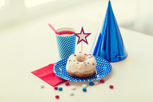 Amerikaanse onafhankelijkheidsdag, viering, patriottisme en vakantieconcept - close-up van geglazuurde zoete donut met sap en snoep in wegwerpservies op 4 juli-feest