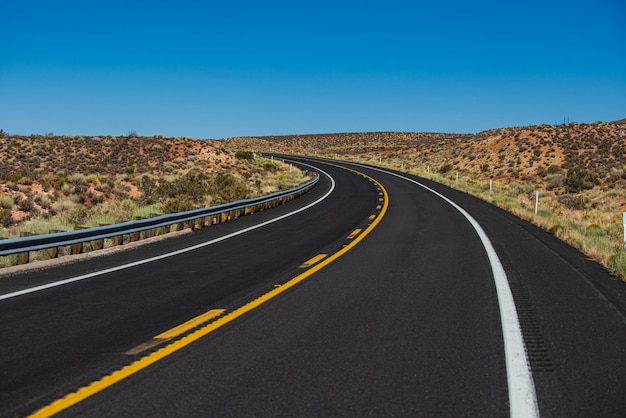 Amerikaanse roadtrip Asfaltweg dwars door het veld met blauwe lucht in de herfst