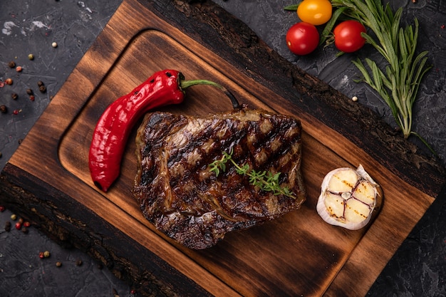 Amerikaanse sappige steak op het bord met kruiden, tomaat en gegrilde groenten. Op een zwarte tafel