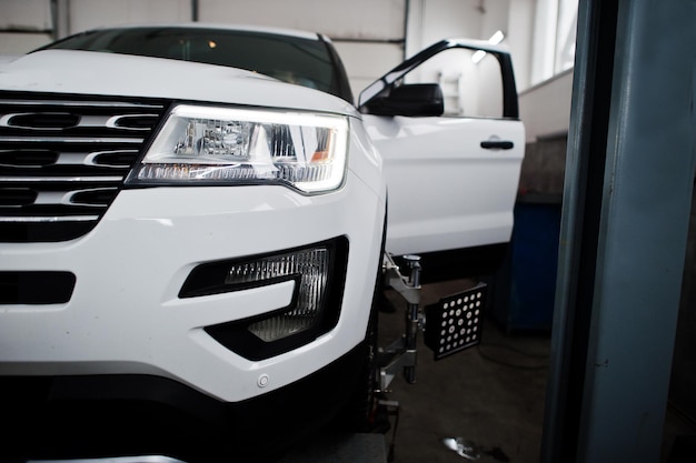 Amerikaanse SUV-auto op standaard voor wieluitlijning camber check in werkplaats van tankstation