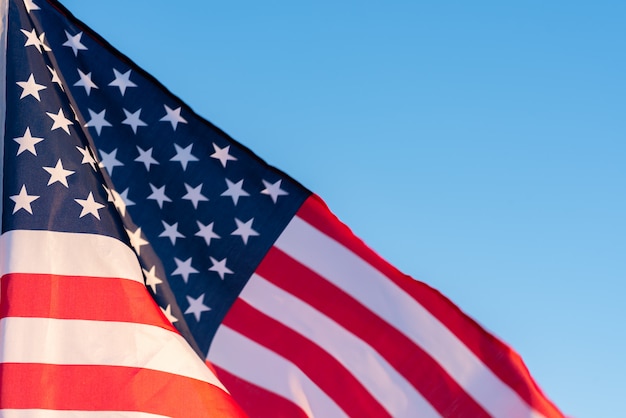 Amerikaanse vlag in een blauwe hemel, close-up. Symbool van Independence Day, vierde juli in de VS.