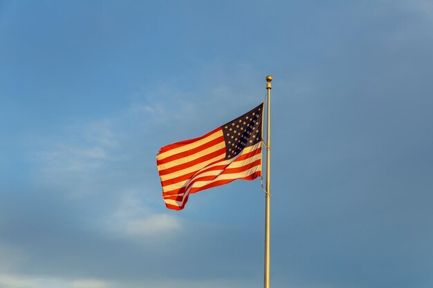 Amerikaanse vlag op vlaggenmast zwaaiend in de wind tegen wolken blauwe lucht en de maan