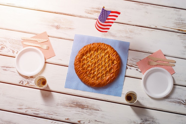 Amerikaanse vlag, taart en drankjes. Tafelvlag naast ronde taart. Hartig ontbijt in Amerikaans café. Eenvoudig dessert geserveerd met koffie.