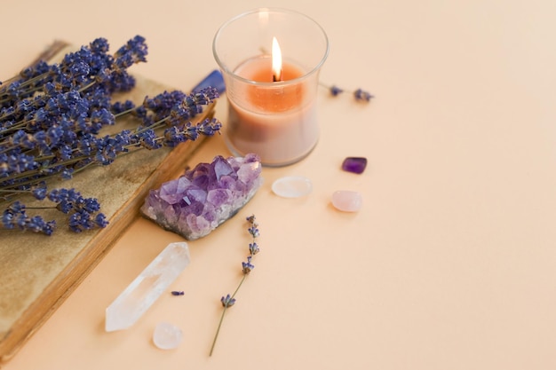 Amethyst natural gemstones burning candle and lavender flowers on a light background copy space