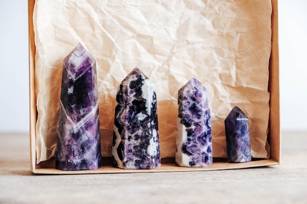 Amethyst polished crystal point in a kraft paper box on wooden background. Copy, empty space for text