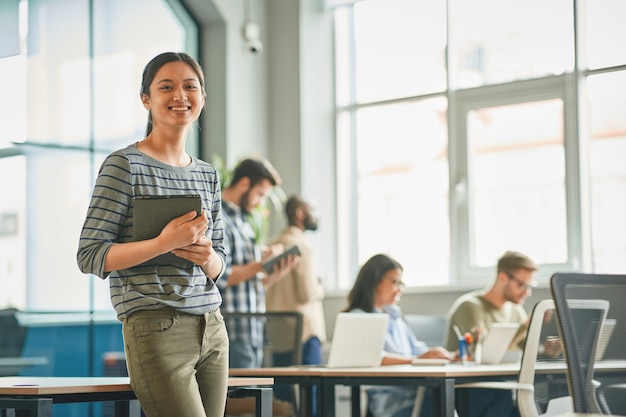 Photo amicable young woman looking accomplished at her workplace