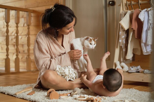 写真 おもちゃと服の中ママと赤ちゃんは猫の友達と静かな瞬間を楽しんでいます - ガジェット通信 getnews