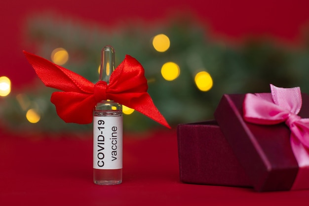 Ampoule of the COVID-19 vaccine near the Christmas tree