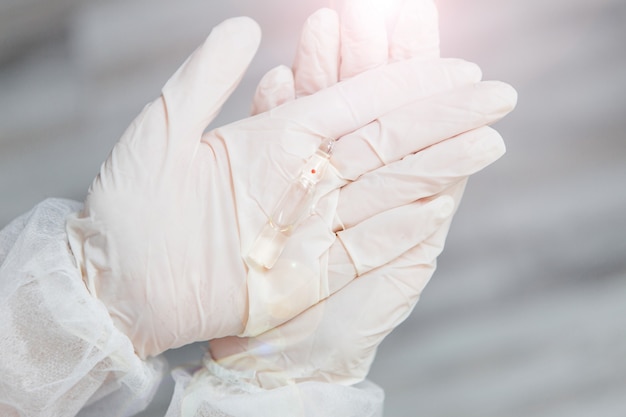 ampoule in the hands of a doctor in white gloves, vaccine
