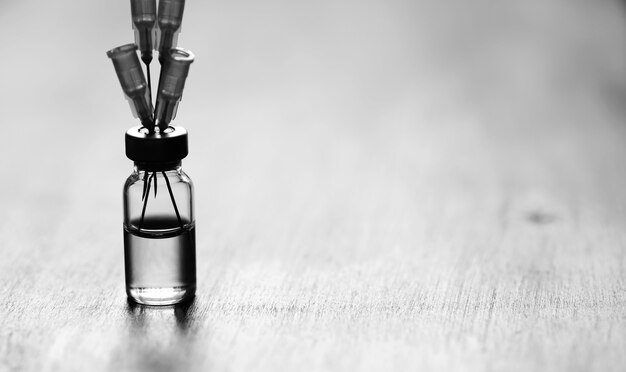 Ampoule and needles from a medical syringe on wooden background