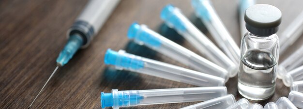 Ampoule and needles from a medical syringe on wooden background