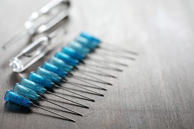 Ampoule and needles from a medical syringe on wooden background